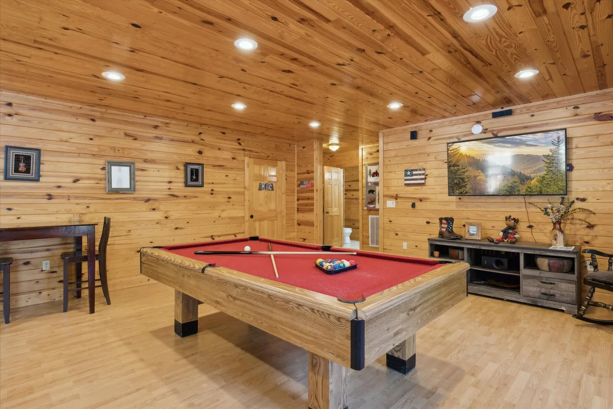 A vibrant game loft featuring a pool table, wood-paneled walls, a wall-mounted TV, and decorative items. The setting is designed for social interaction—perfect for friendly competitions and group entertainment after a day of exploring.