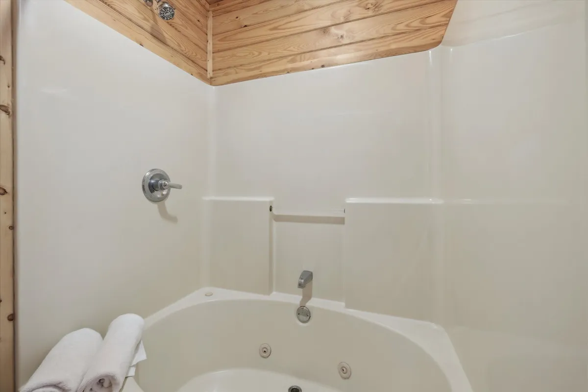 A serene bathroom with a jacuzzi tub, wooden ceiling, and neatly arranged towels—offering a luxurious and private space for relaxation and wellness routines.