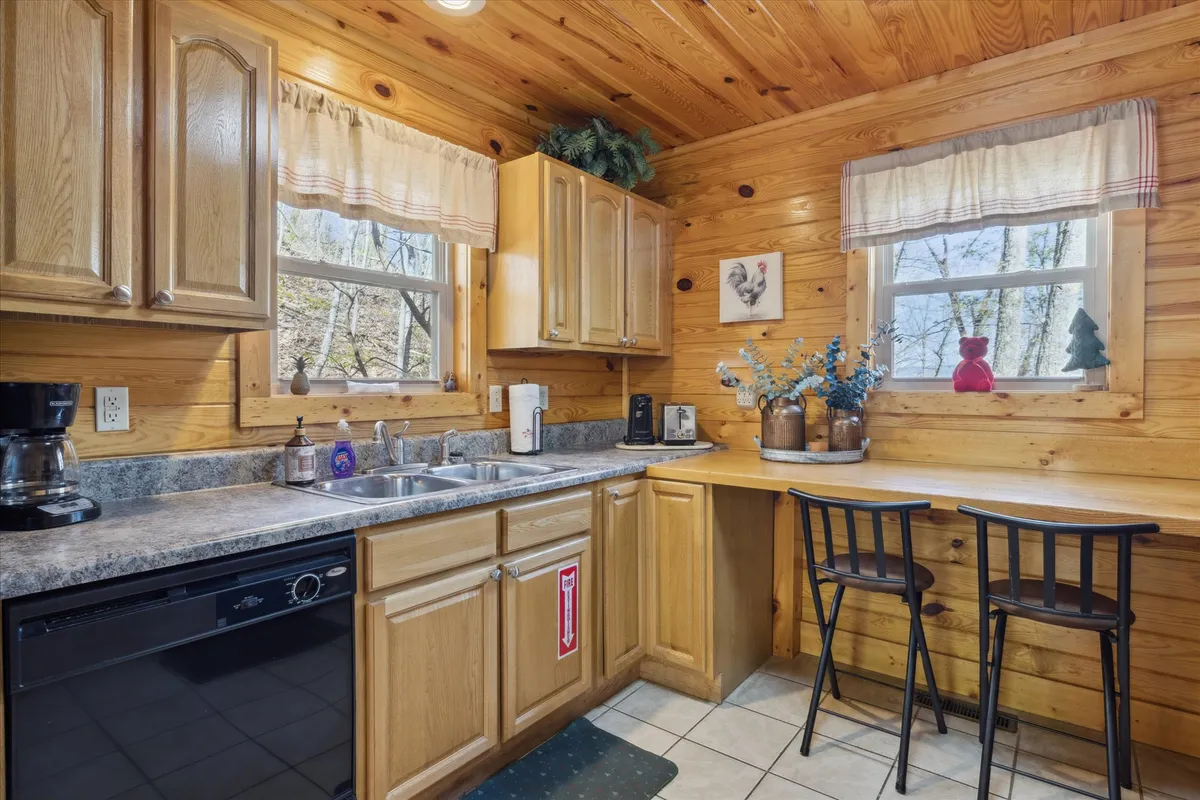 A welcoming kitchen scene featuring expansive countertops, wooden cabinetry, a view into the adjacent dining area with chairs, and decorative accents on the counters. Soft morning sunlight streams through the windows, creating a cheerful atmosphere.
