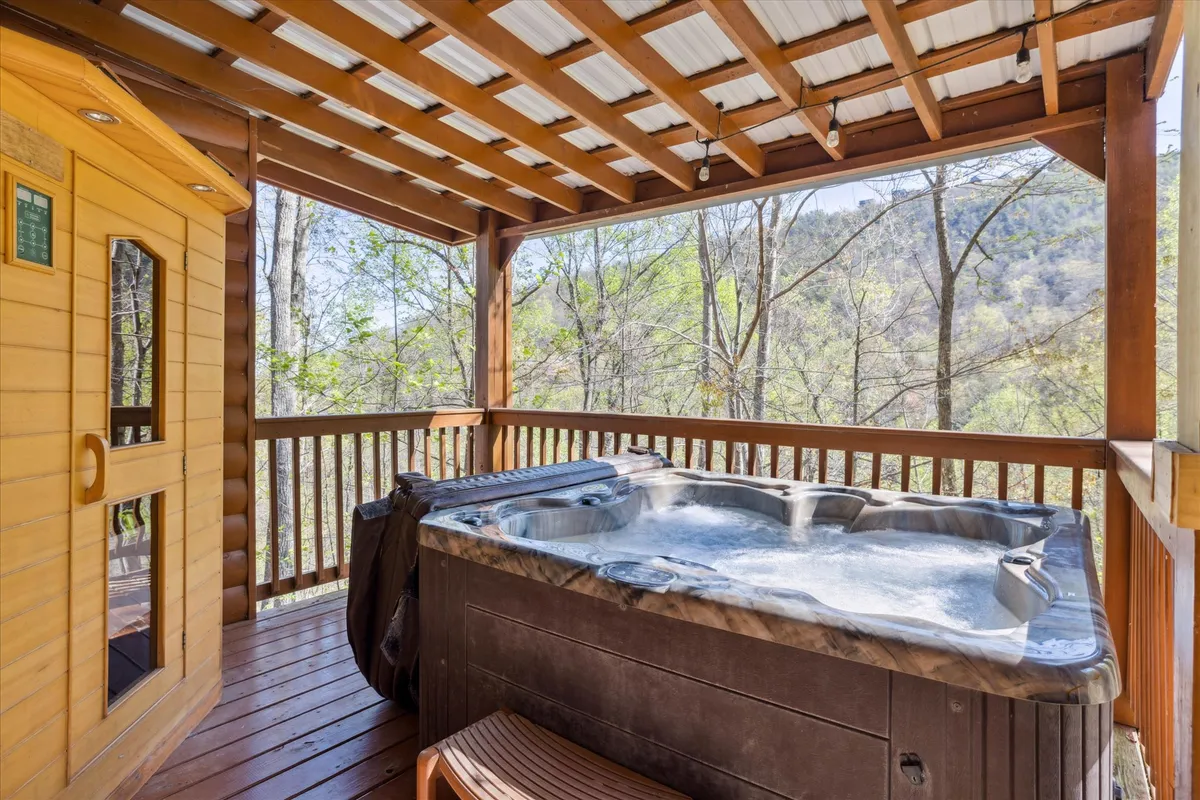 This exterior image captures the private hot tub and cedar sauna positioned on a spacious wooden deck, all set against a picturesque backdrop of mountains. The deck also offers space for seating and relaxation, inviting guests to unwind while soaking in the natural beauty.